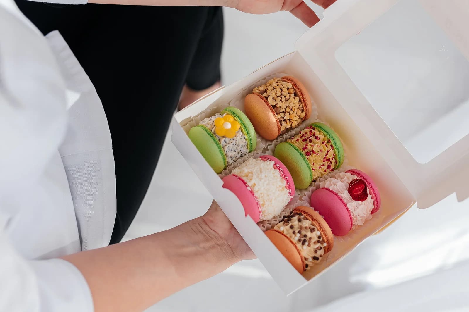 Holding an open box of fresh macarons