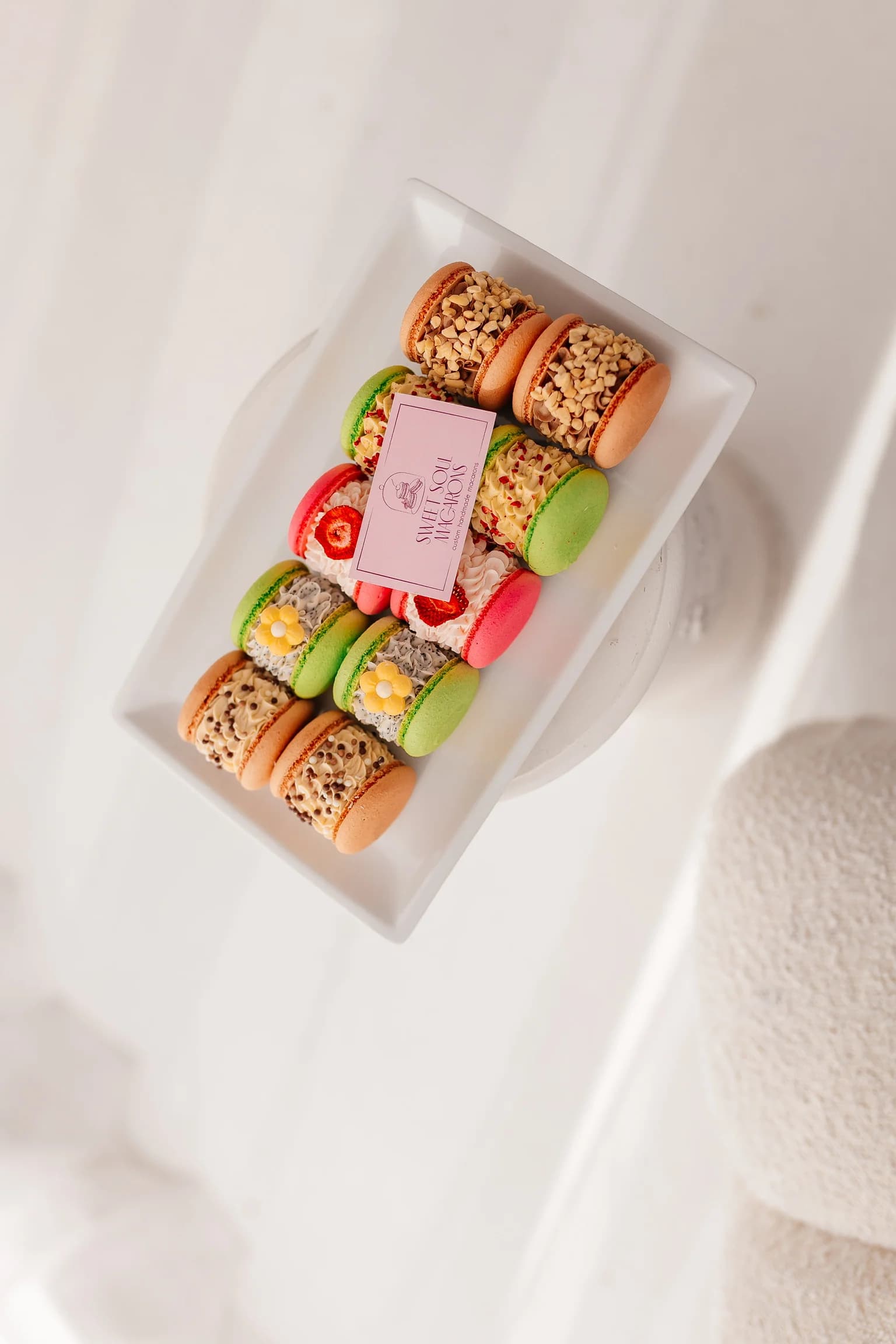 Twelve macarons arranged in a grid on marble